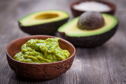Guacamole with avocado on wooden table